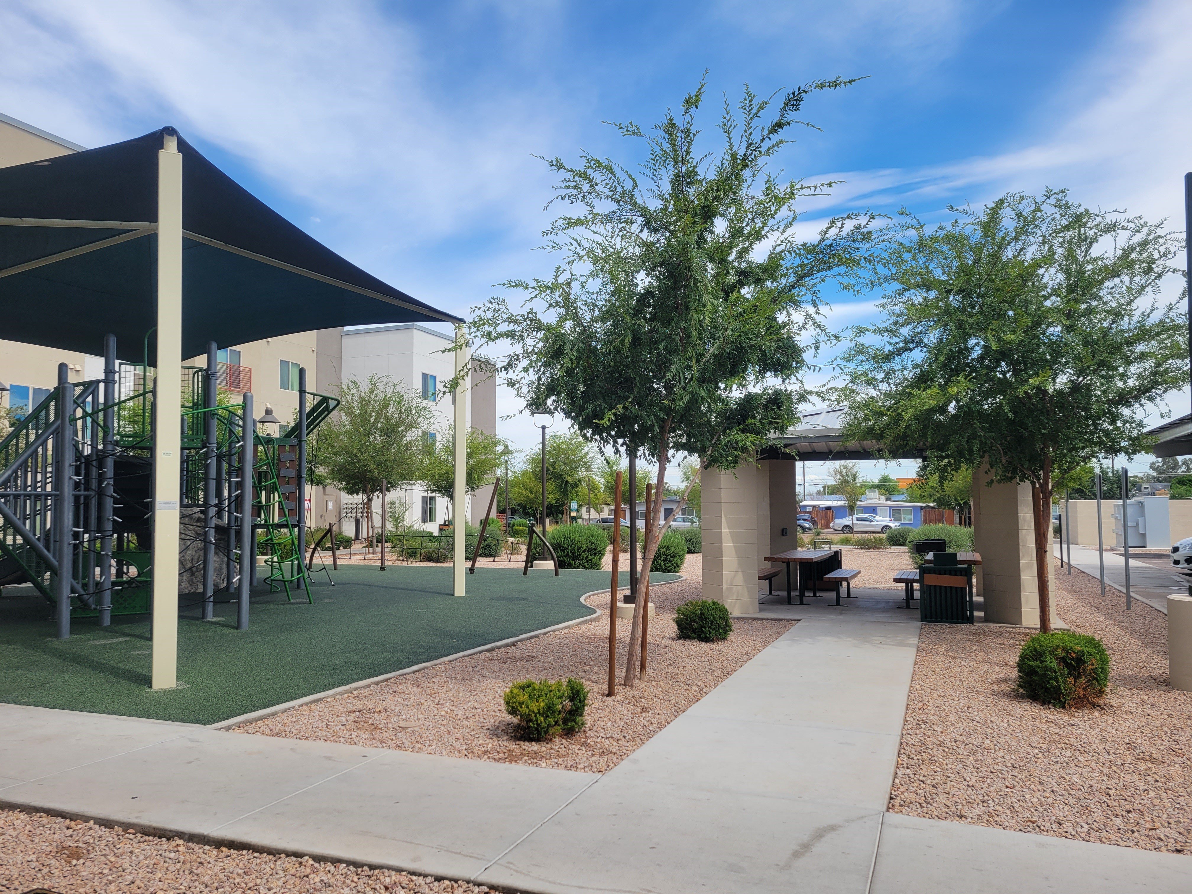 a courtyard with a playground and tables and chairs